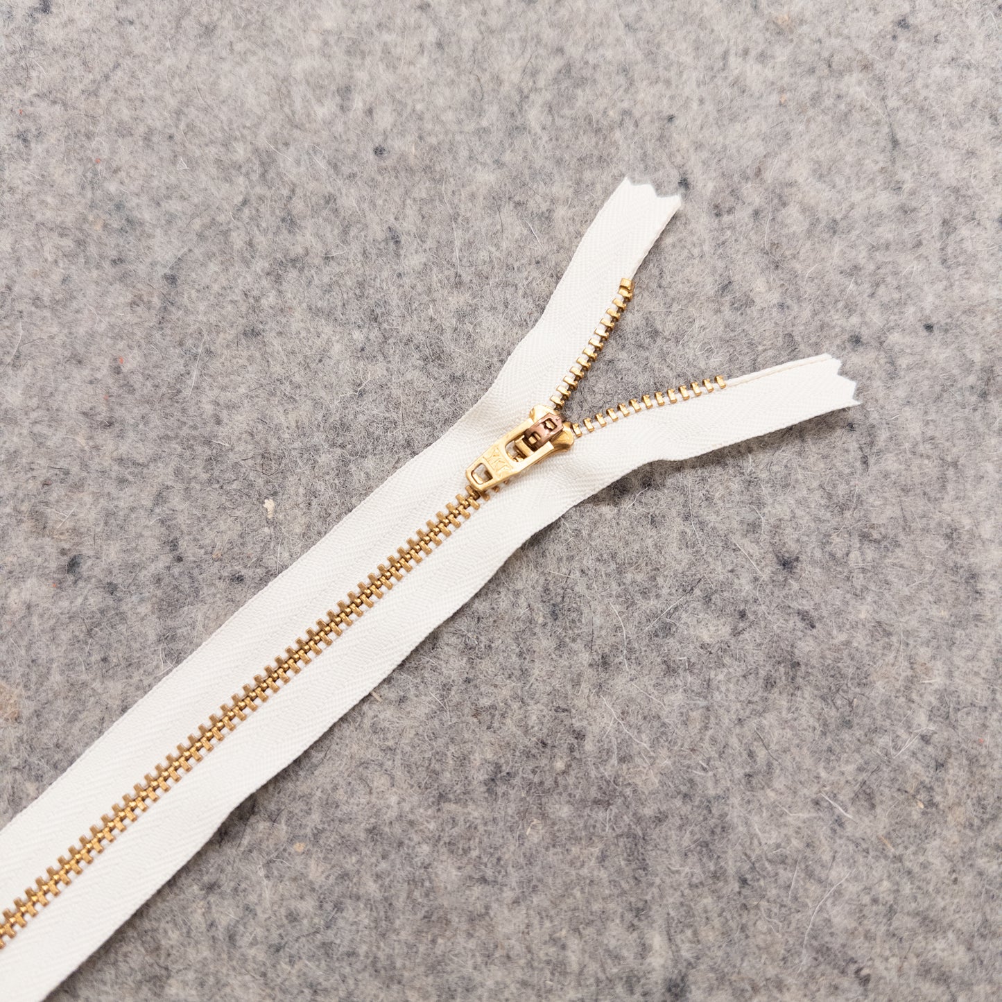 White zipper with gold teeth on a gray textured background