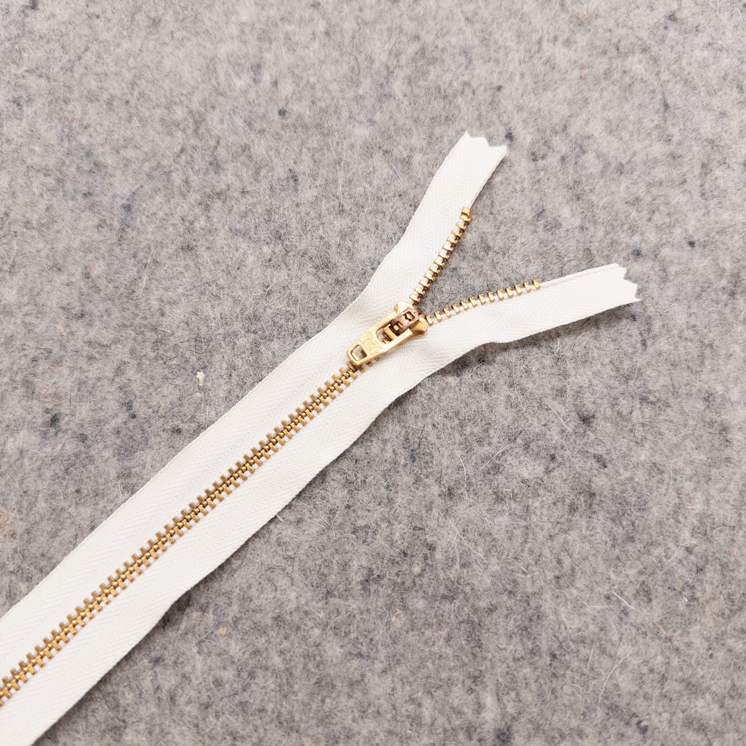White zipper with gold teeth on a gray textured background
