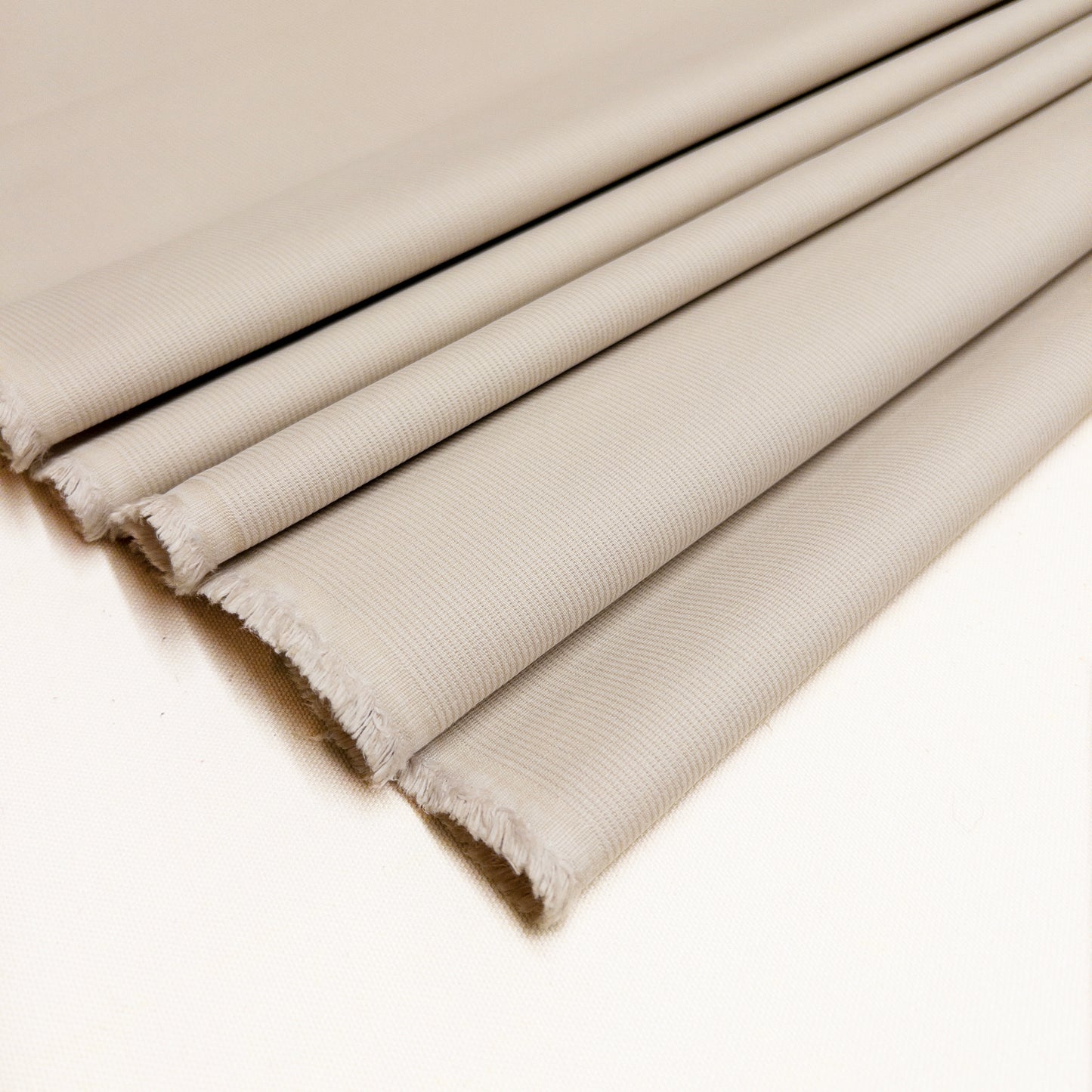 Folded fabric is 100% cotton bottom weight garment fabric in a stone white.