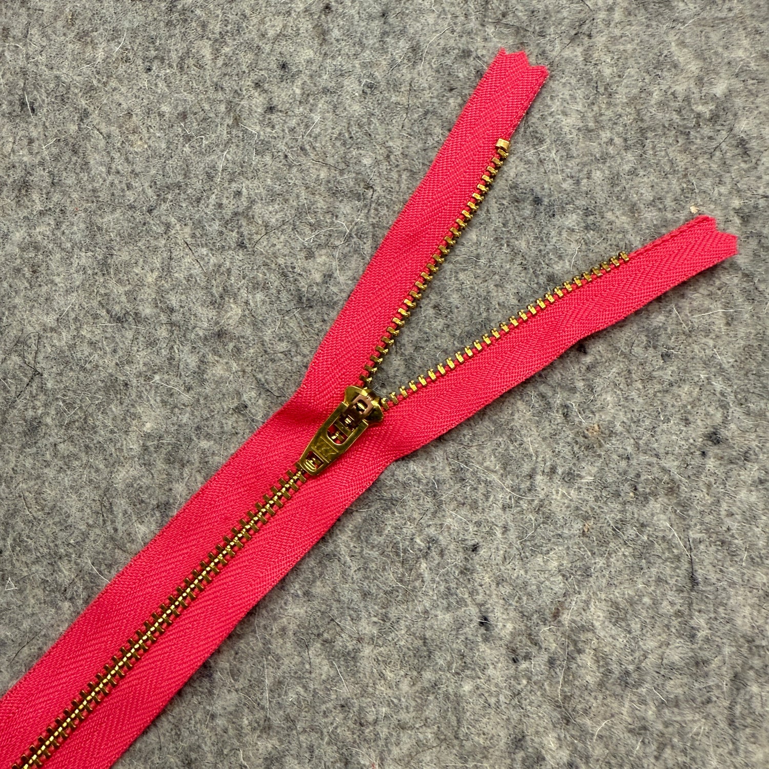 Pink zipper with gold teeth on a gray textured background