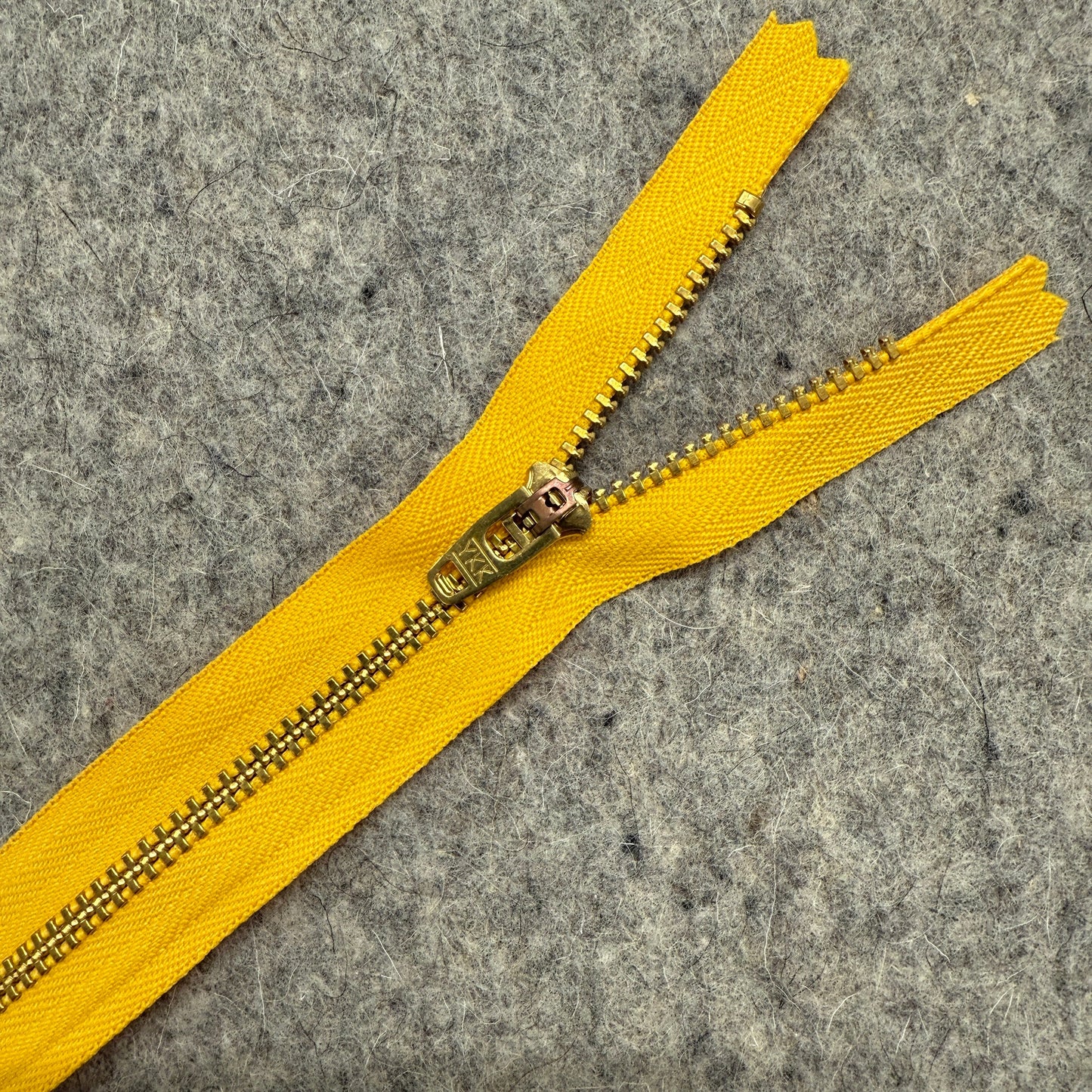 Yellow zipper with gold pull on a gray background