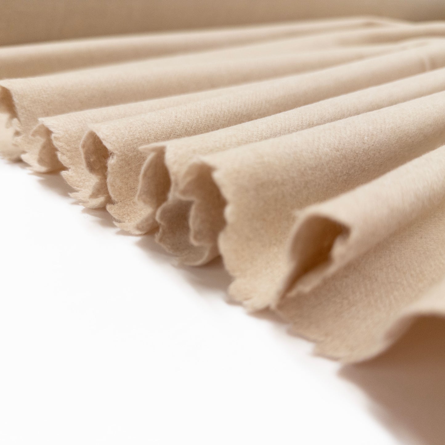 Italian wool garment fabric suiting in a cream color shown folded in a ribbon