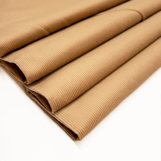 14 wale 100% cotton corduroy fashion fabric in a light brown shown folded.