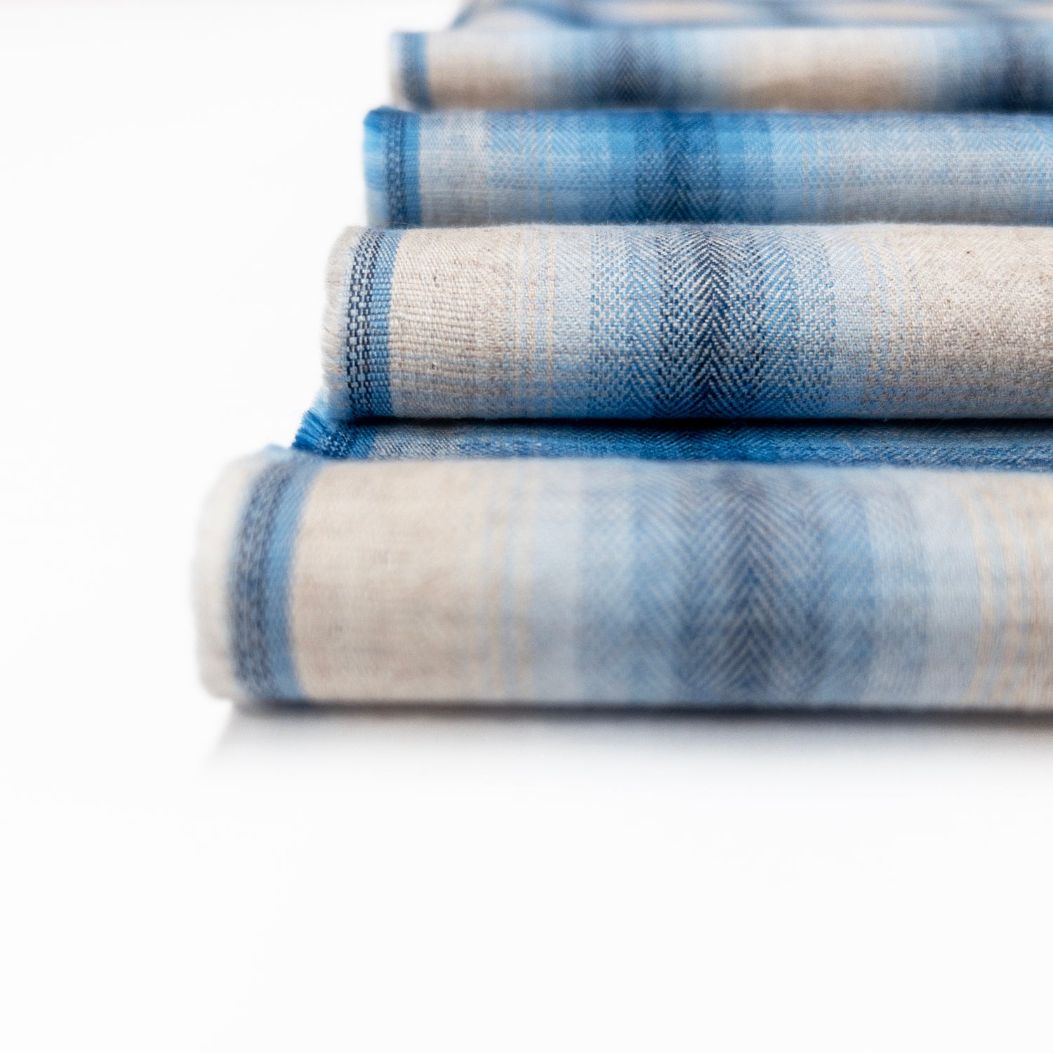 Detail view of this cotton shirting fabric in shades of blue and natural shows the herringbone weave