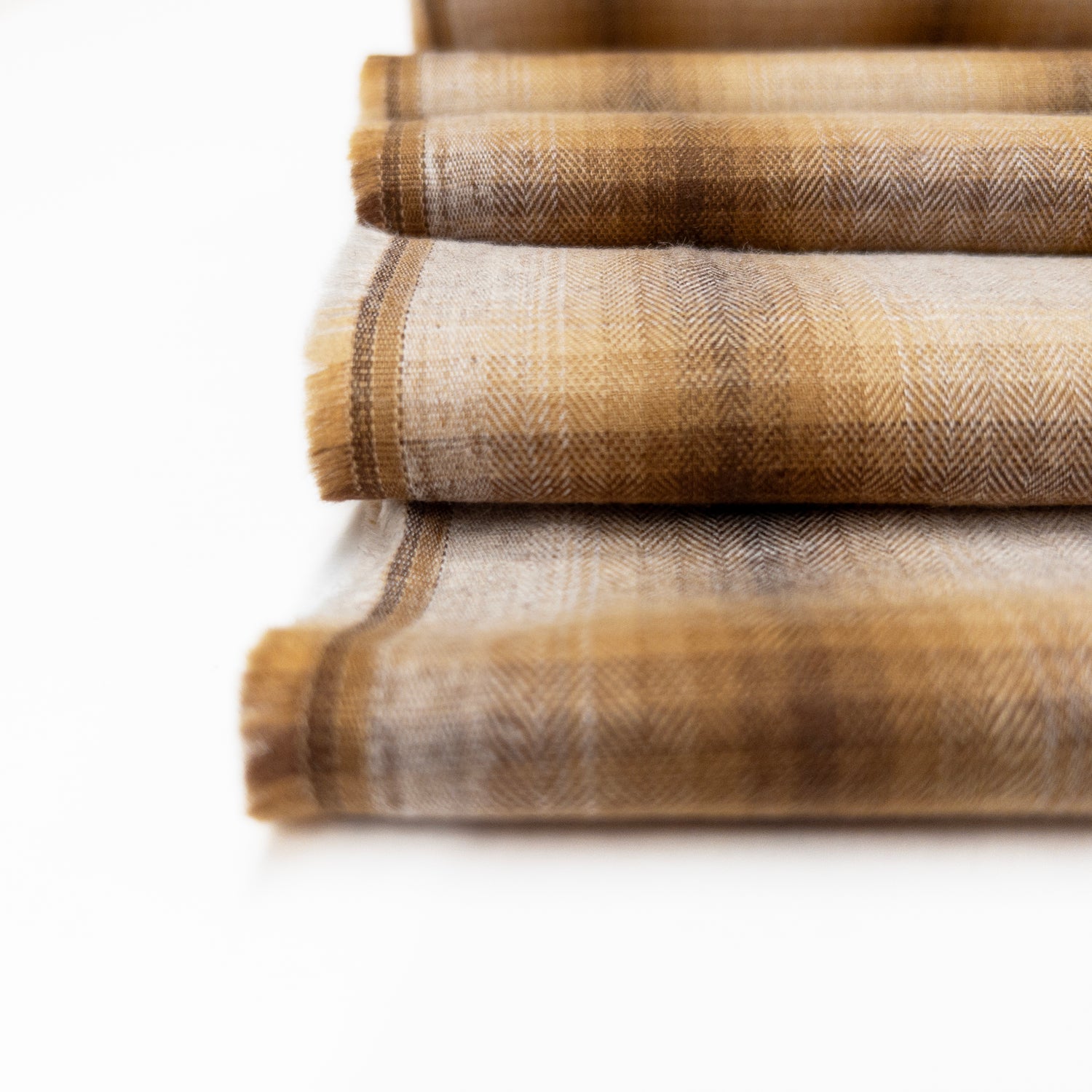 Detail view of cotton shirting garment fabric with a herringbone weave in browns and natural colors