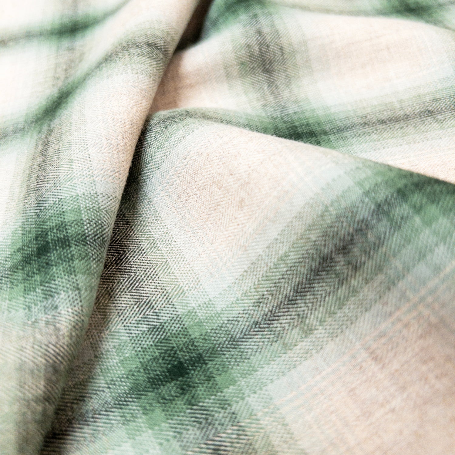 Close up view of this garment fabrics herringbone weave and colorways of natural fading to a deep green.