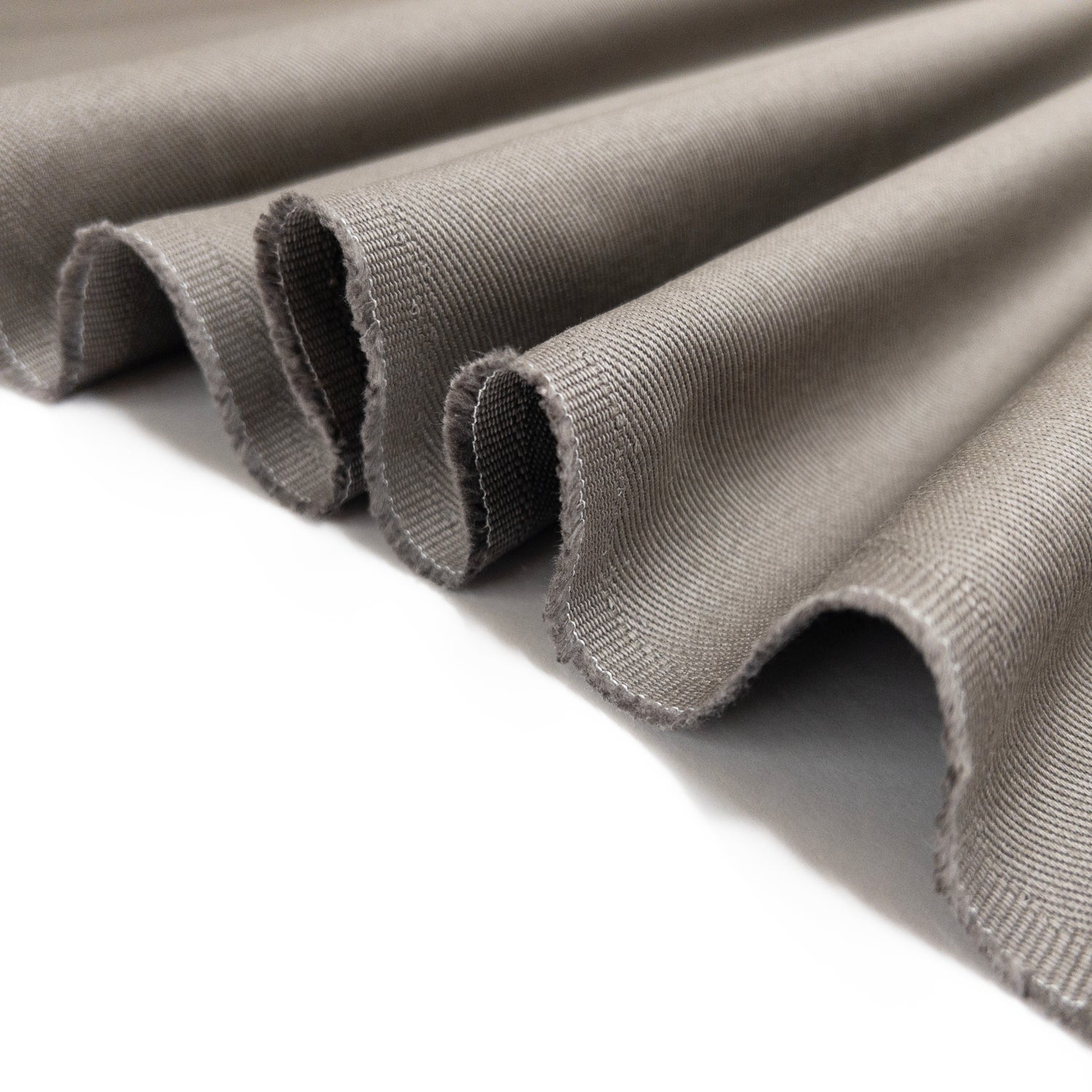 Heavy weight cotton twill apparel fabric in warm grey shown folded in a ribbon