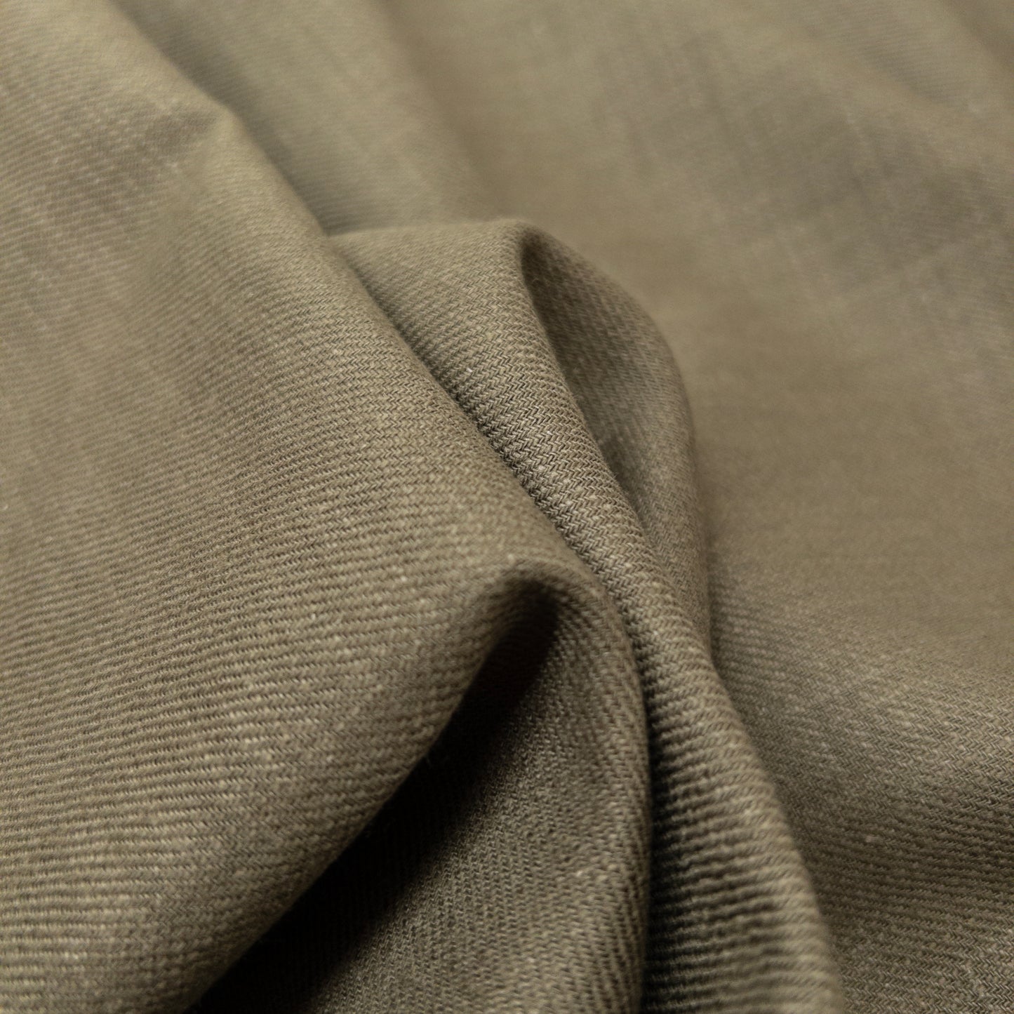 View of the surface of this cotton shirting fabric in an olive green.