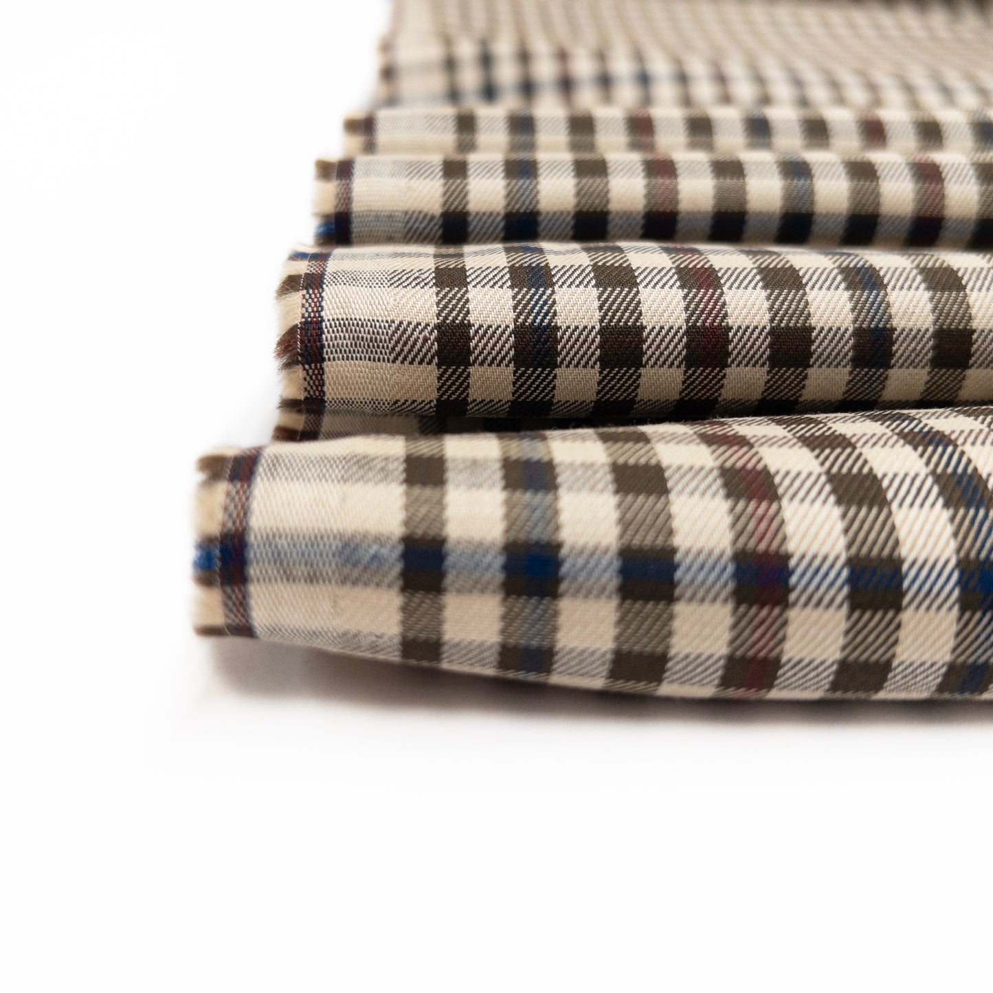 Detail view of check cotton shirting is a olive colorway over a white-beige background.