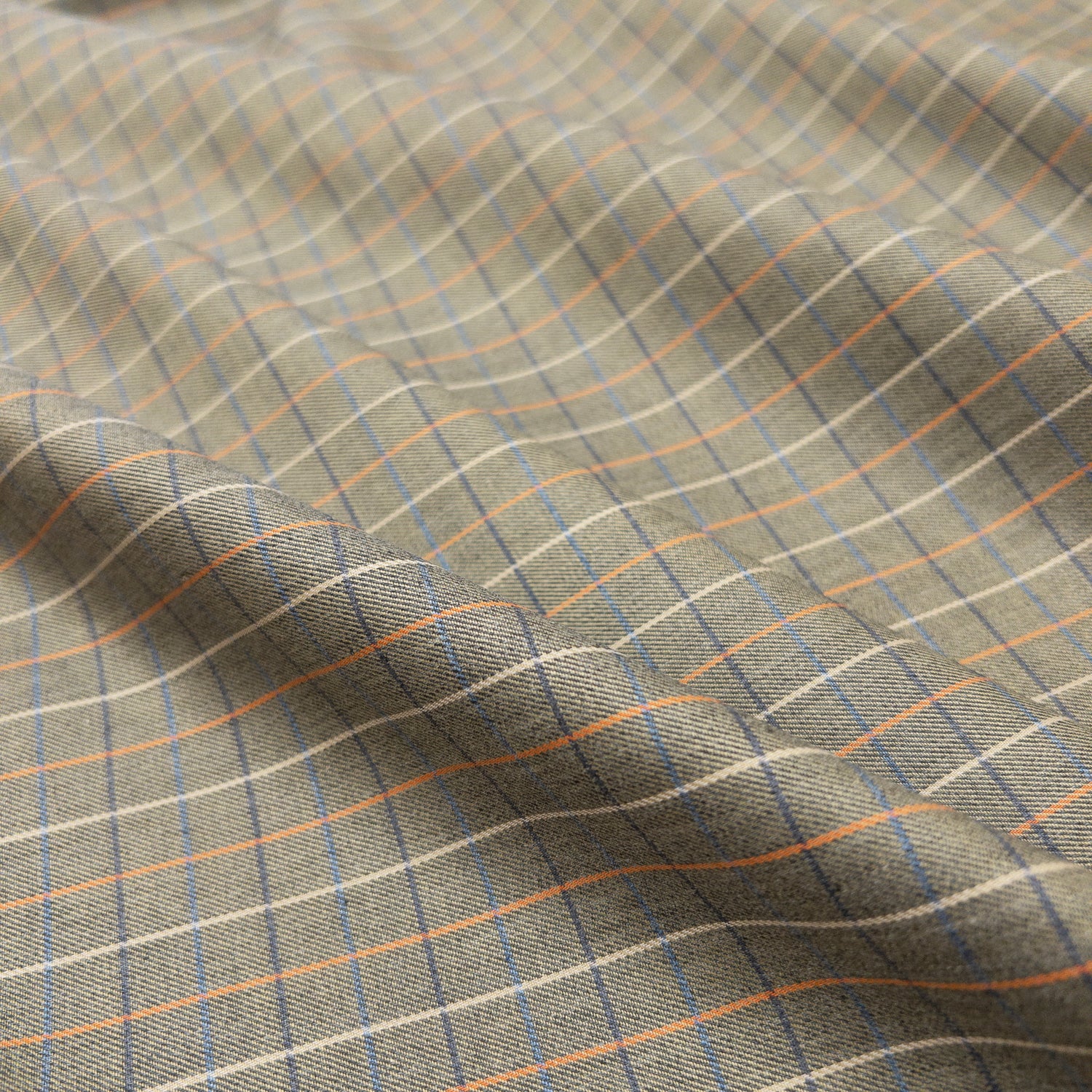 Cotton shirting in olive from above shows design of colored blue and orange grid lines.