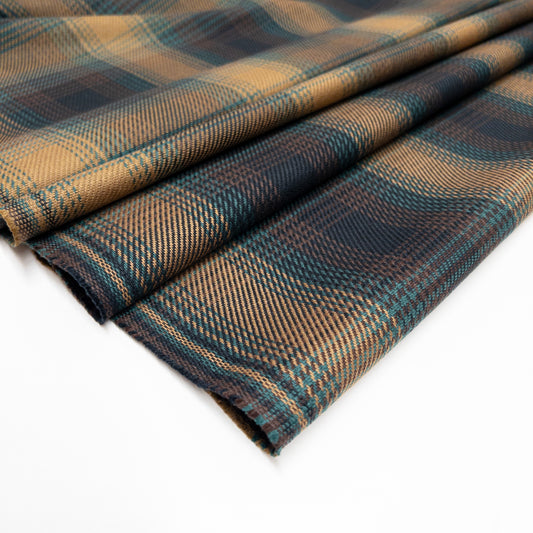 Tartan plaid with a twill weave in brass, green and brown shown folded.