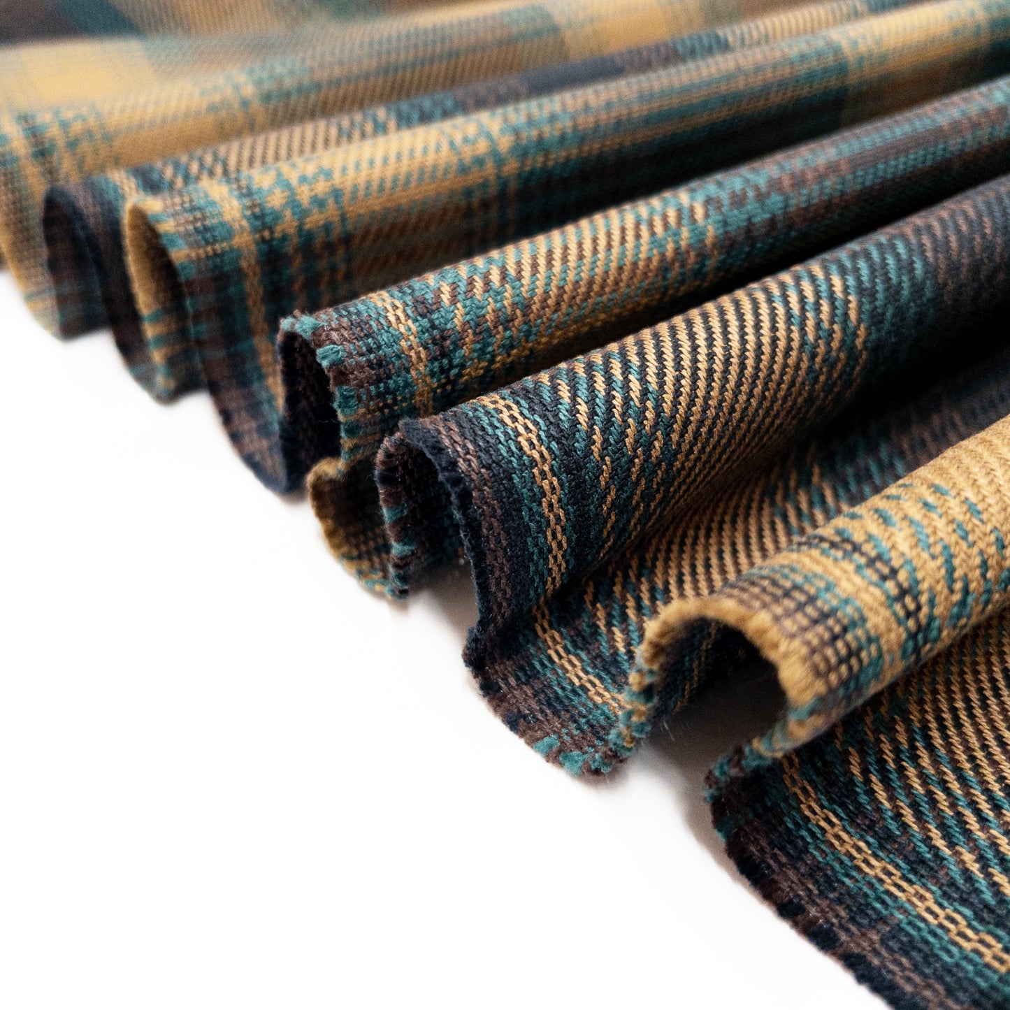 Tartan plaid twill folded in a ribbon to illustrate the soft drape of this 100% organic cotton garment fabric.