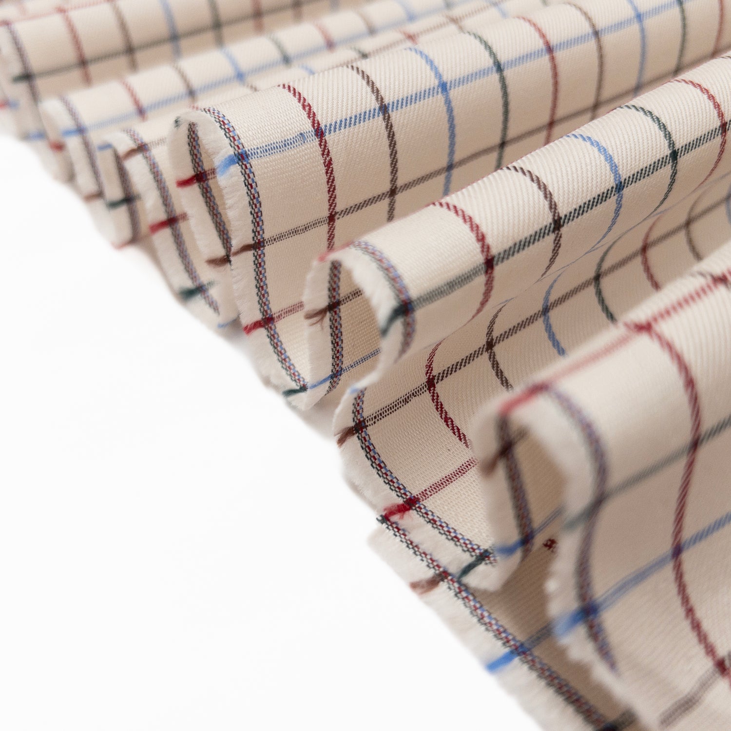 Tattersall plaid in 100% cotton with a multi color grid design over soft white in a twill weave shown folded in a ribbon.