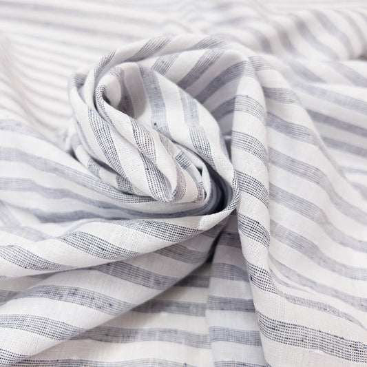 This lightweight cotton and linen garment fabric features a white and faded blue  stripe shown here wraped in a spiral to demonstrate the soft drape.