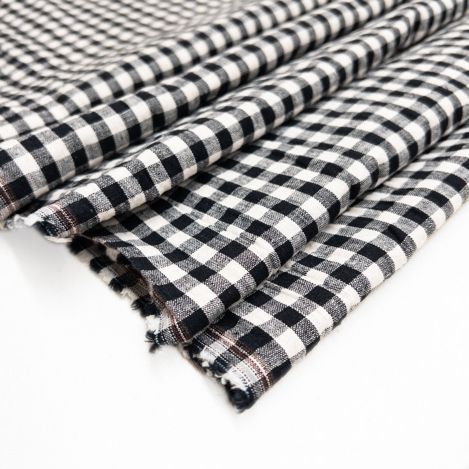 Black and natural gingham from a blend of cotton and linen this garment fabric is shown folded over itself from above.