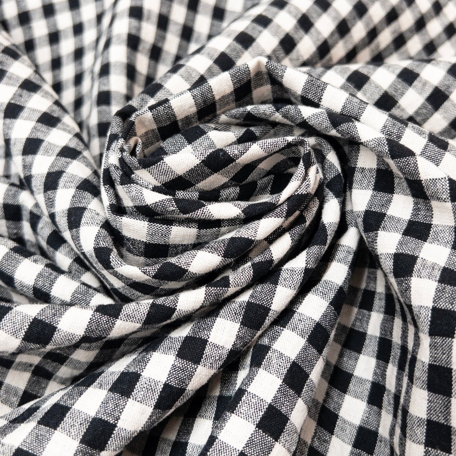 Garment fabric of cotton and linen in a black and natural yarn gingham shown in a spiral motif.