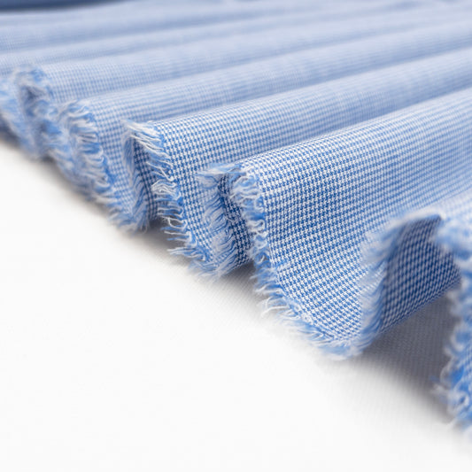 Very lightweight garment fabric in blue and white folded in a ribbon to show soft drape.