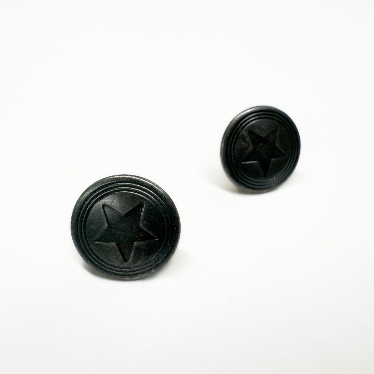 Image of two jeans buttons in antique silver with a ring and star pattern.