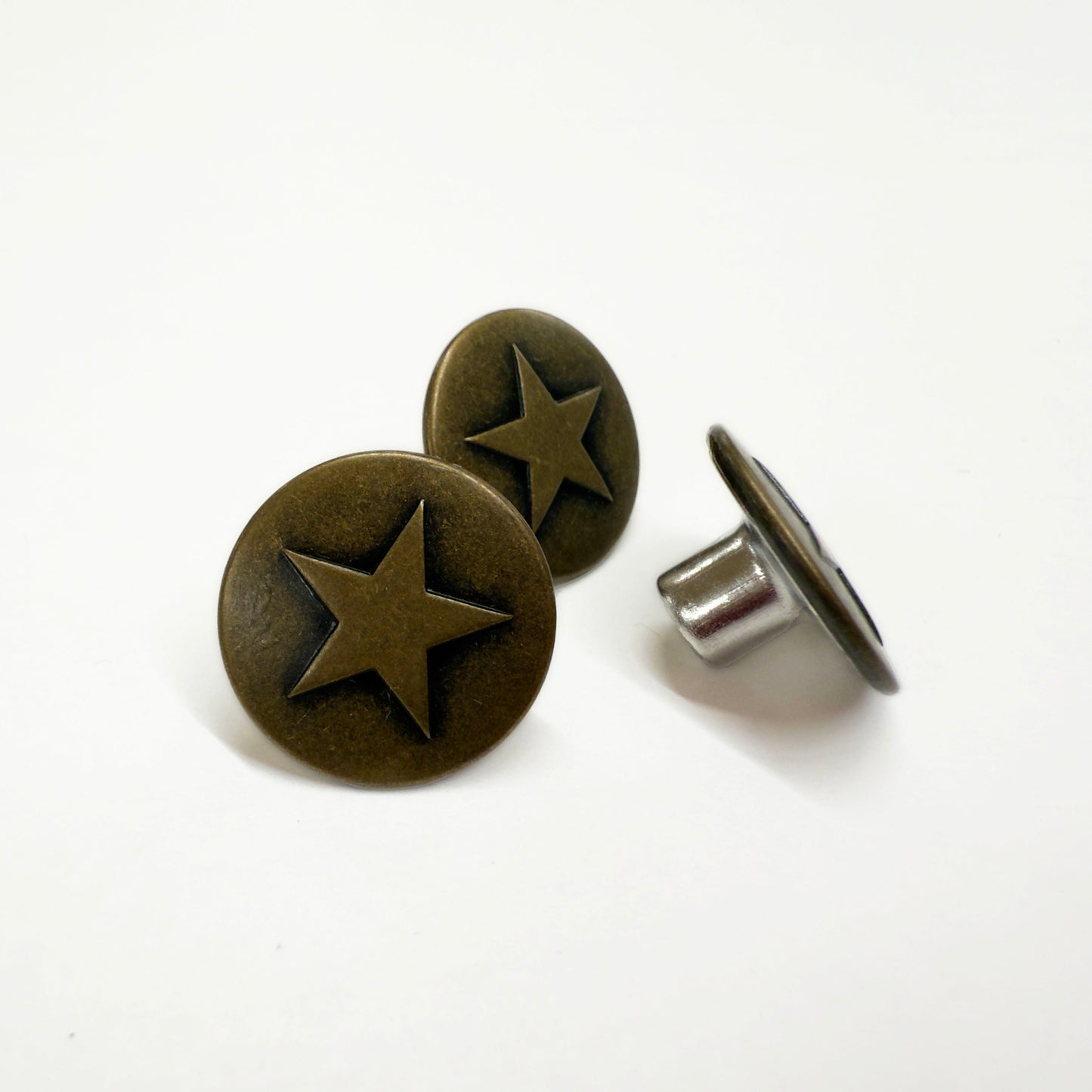 Image of three 18mm jeans buttons with a single star relief in antique brass.