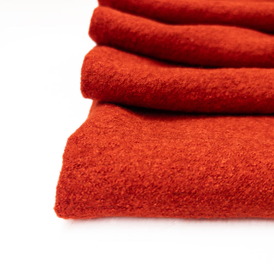 Red orange boiled wool garment fabric shown close up to demonstrate the fabrics textured surface.