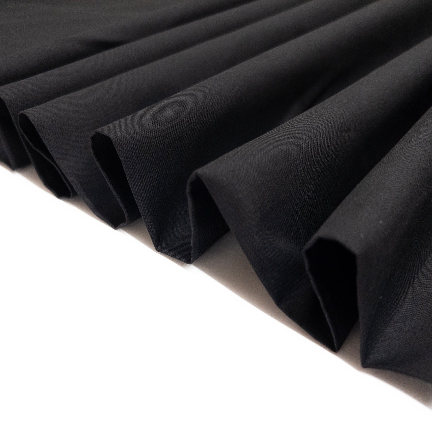 Black cotton voile shown folded as a ribbon to demonstrate fabric stiffness and structure