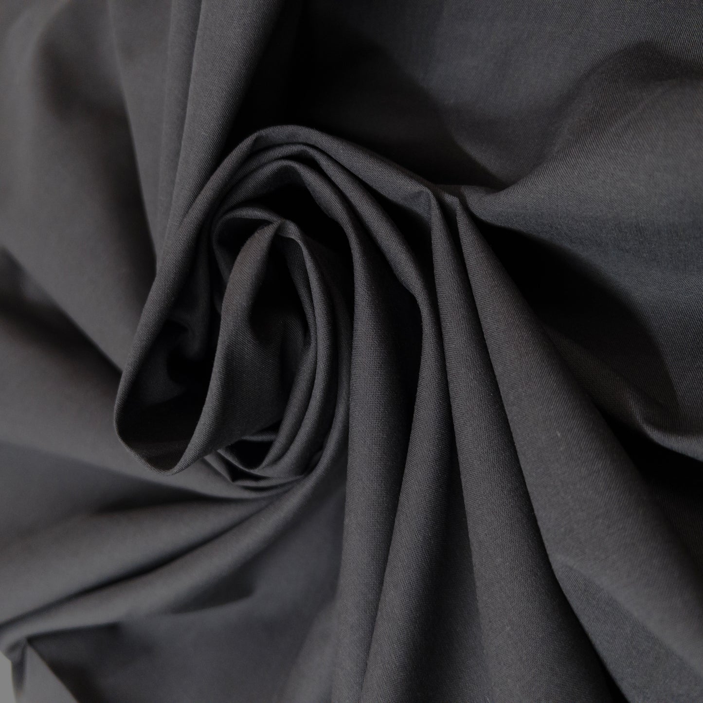 Jet black 100% cotton voile garment fabric is twirled around itself to show fabric stiffness