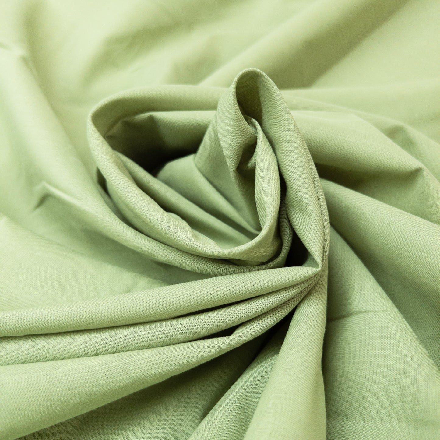 The smooth face of this cotton voile is evedent in this twrled view of the apparel fabric