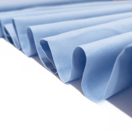 Faded blue garment fabric shown gfolded in a ribbon to demonstrate a crisp drape.