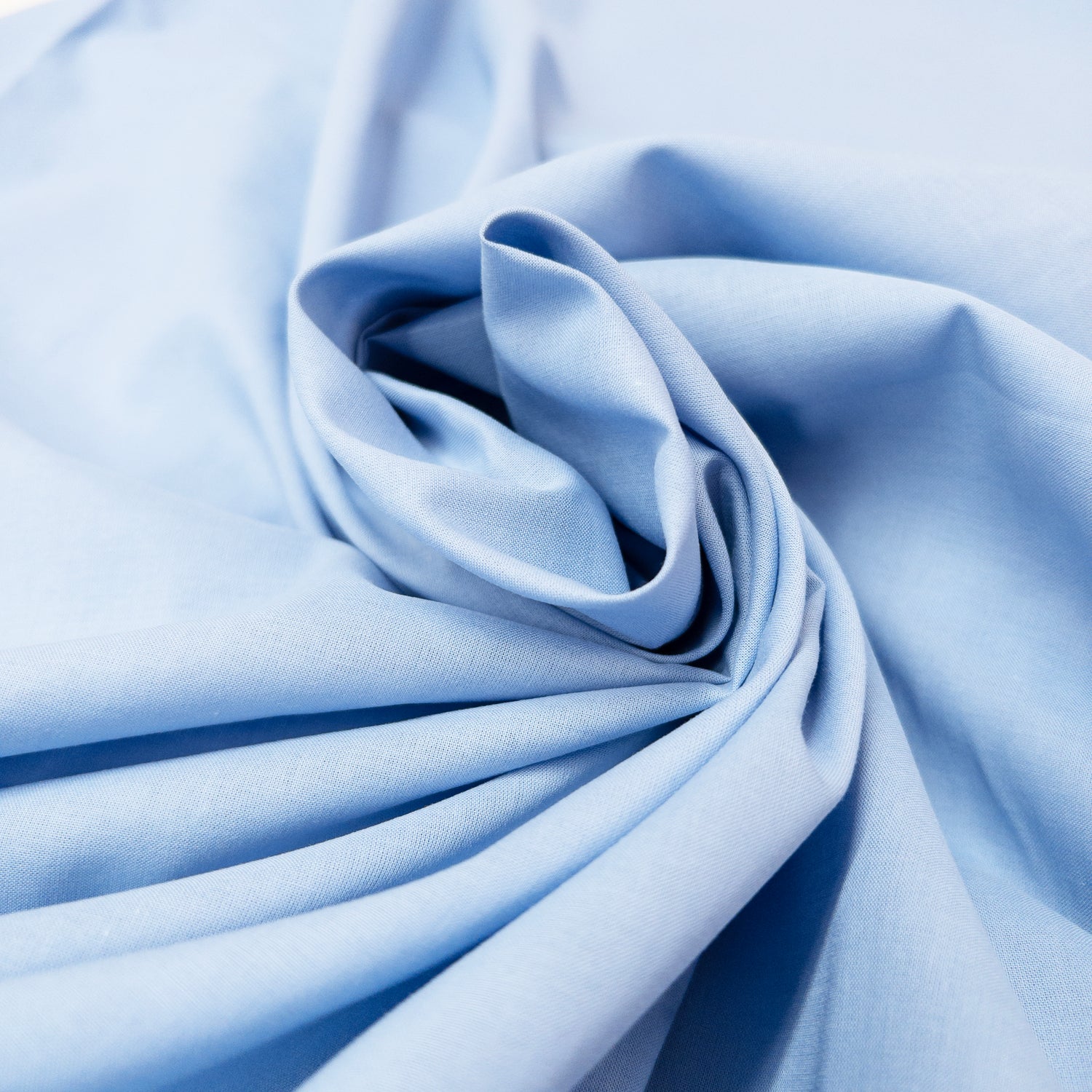 Soft blue cotton voile garment fabric shown in a spiral.