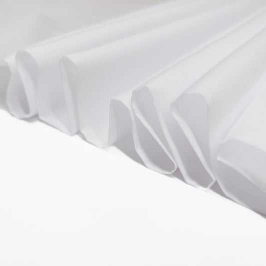 Cotton voile garment fabric folded in a ribbon to demonstrate crisp drape.