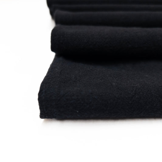 close up of fabric folded in black cotton with a slub texture surface