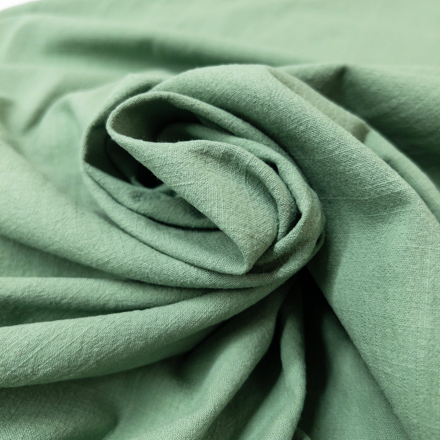 Oeko-Tex certified muted green cotton fabric in a spiral display