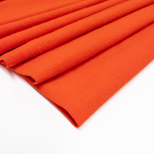 Bold and bright fiery orange fabric shown in folds