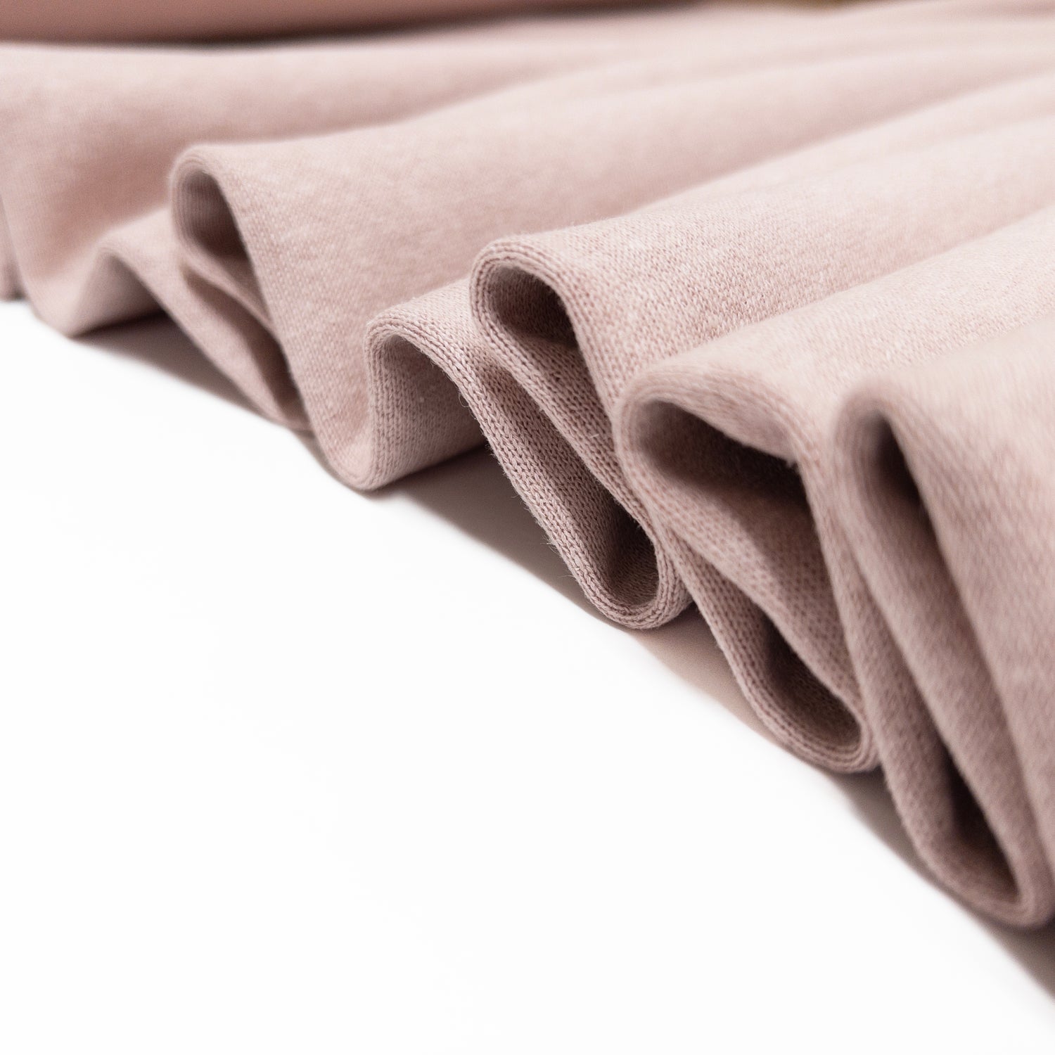 Garment fabric is folded in a ribbon to show the soft drape of this blush knit.