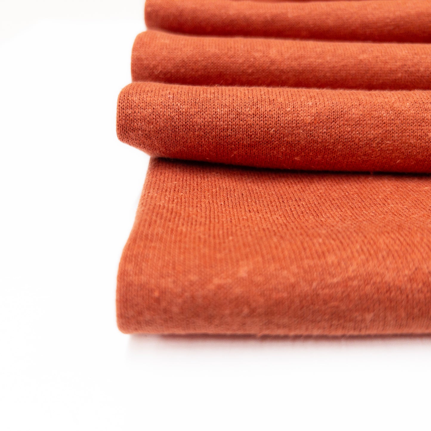 Detail view of the heatered knit face of this fleece back garment fabric in a coral color.