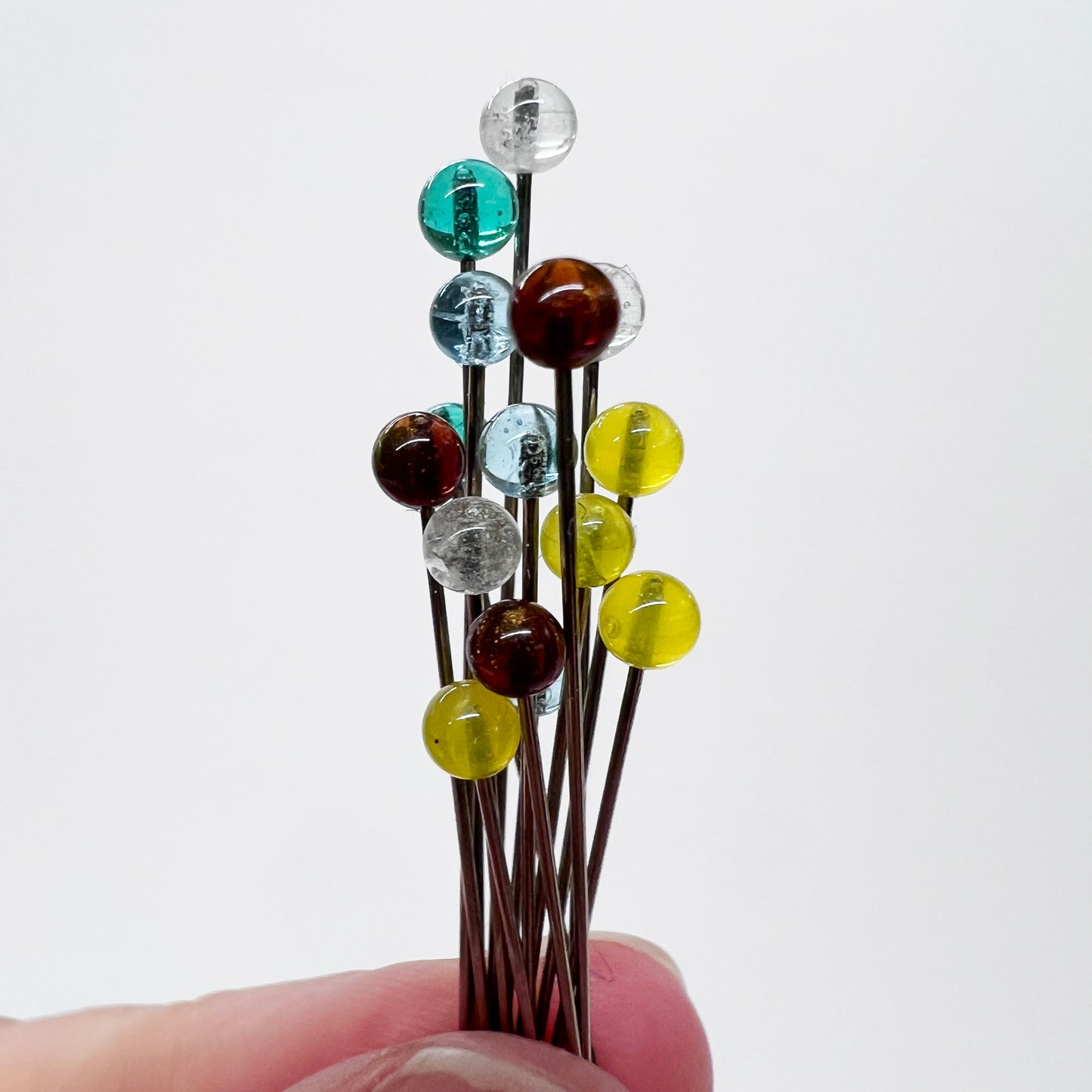 Several glass head pins for sewing with a nickel plated stainless steel shaft.