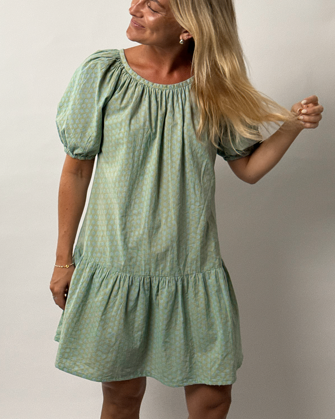 Woman wearing a green dress against a plain background