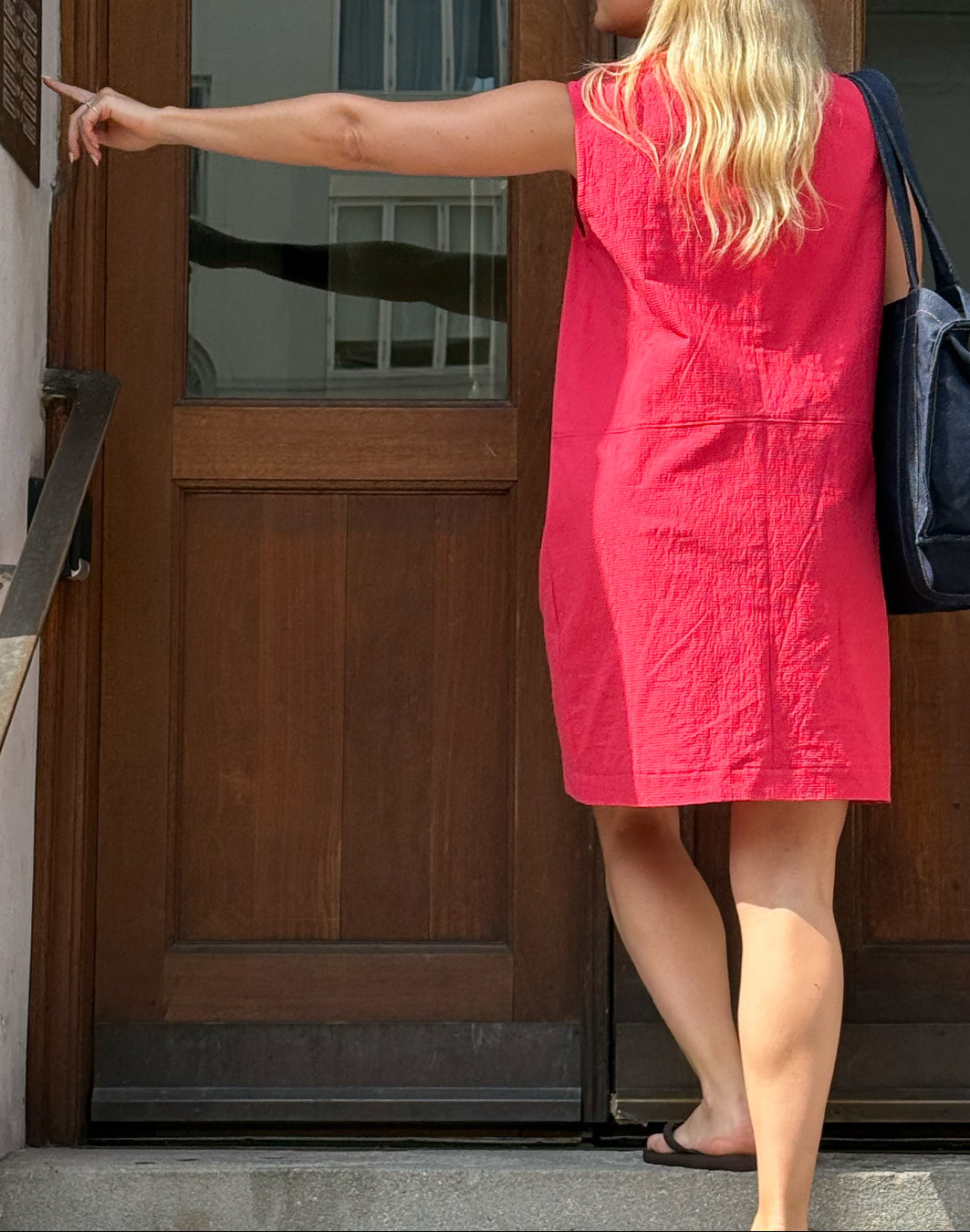 Woman in a red dress standing at a wooden door