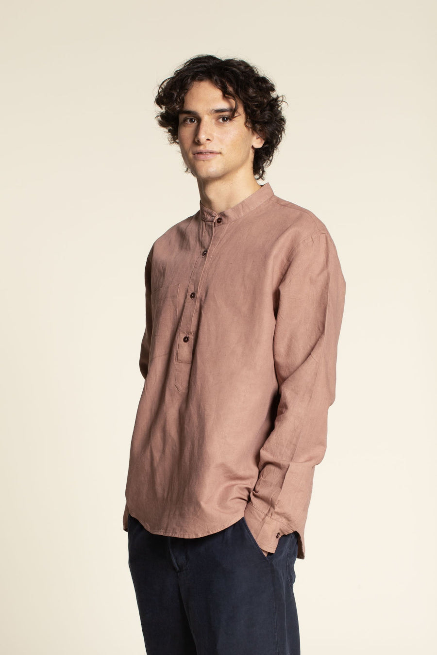 Man wearing a brown shirt against a beige background