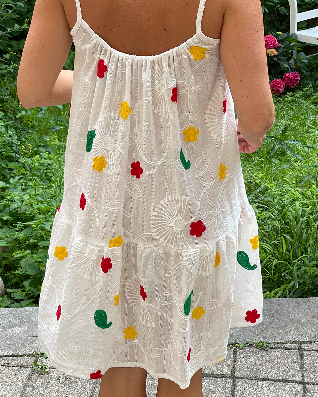 White dress with colorful floral patterns worn by a person outdoors.