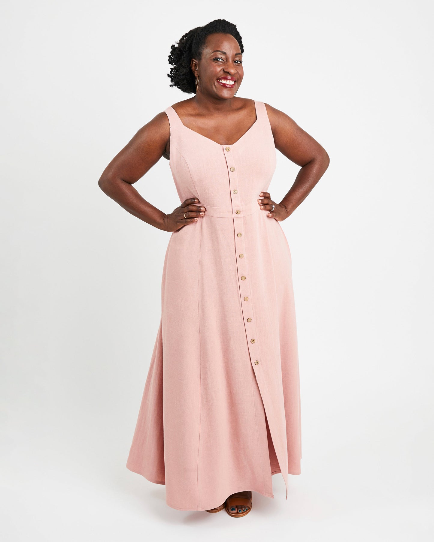 Woman wearing a pink sleeveless dress with buttons on a white background. This is the Holyoke Maxi Dress & Skirt sewing pattern from Cashmerette.