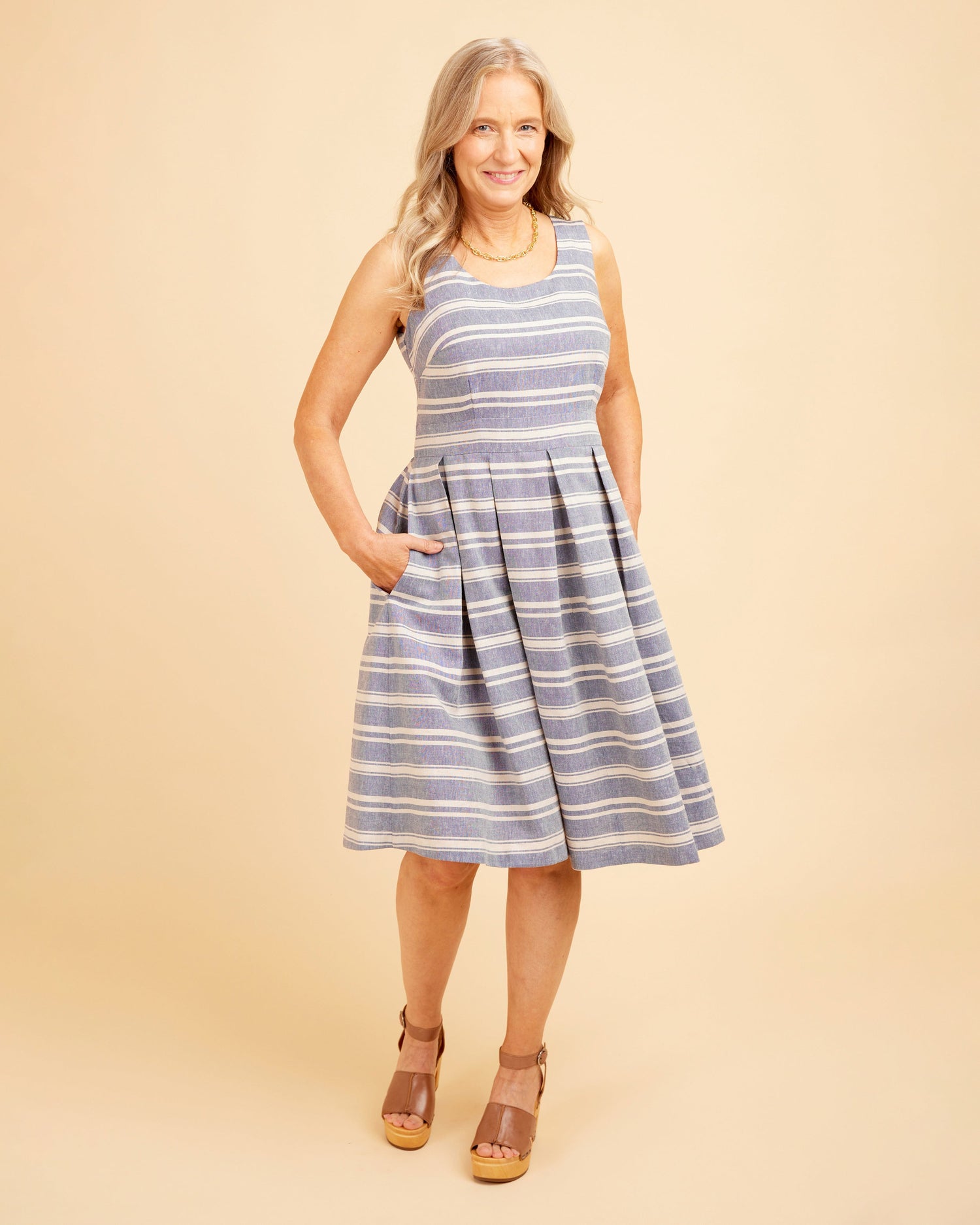 Woman wearing a blue and white striped dress on a beige background. This dress is the Upton Dress & Skirt sewing pattern from Cashmerette.