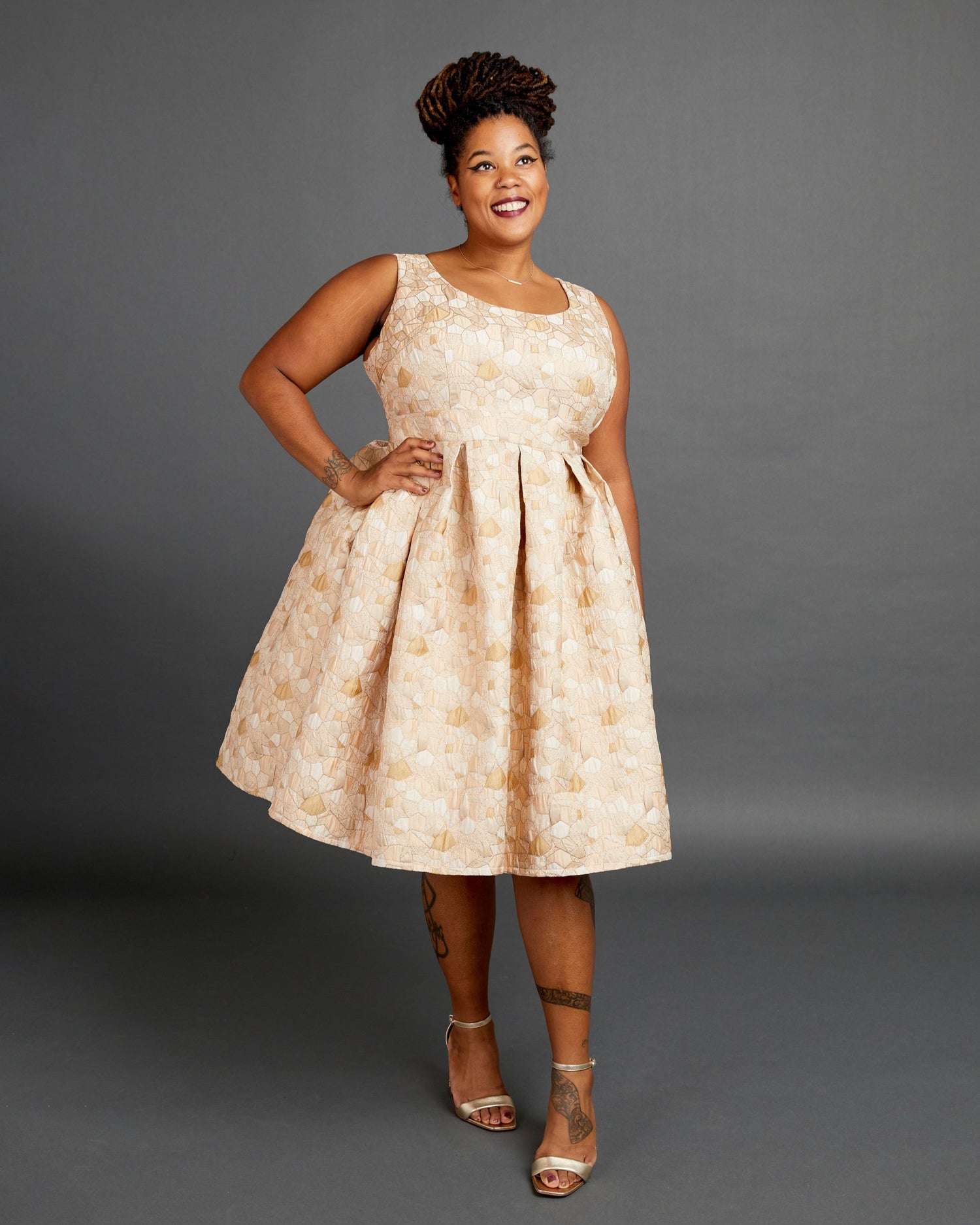 Woman wearing a beige floral dress against a gray background. This dress is the Upton Dress & Skirt sewing pattern from Cashmerette.