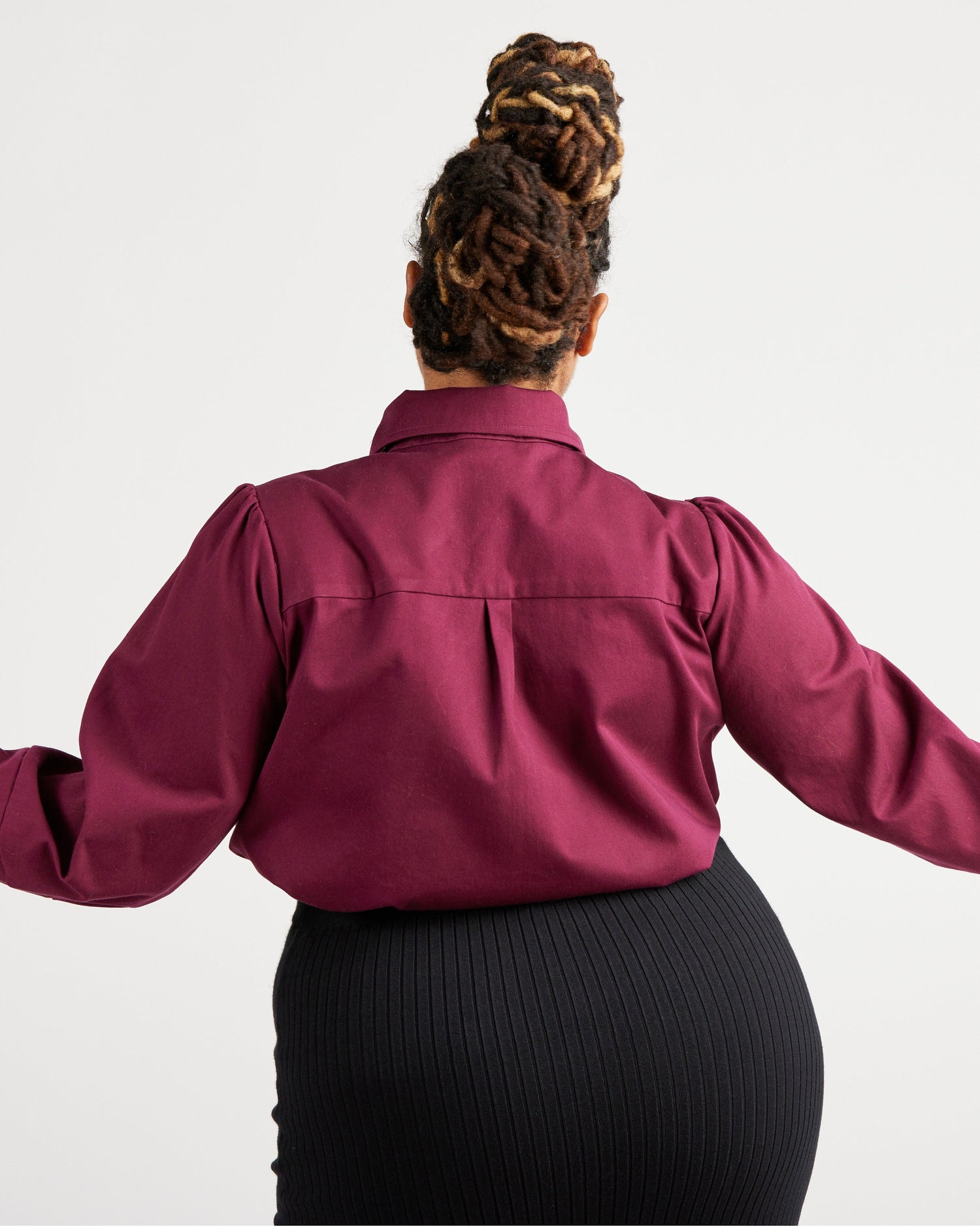 Person wearing a burgundy shirt with long sleeves on a white background. This top is the Vernon Shirt sewing pattern from Cashmerette.