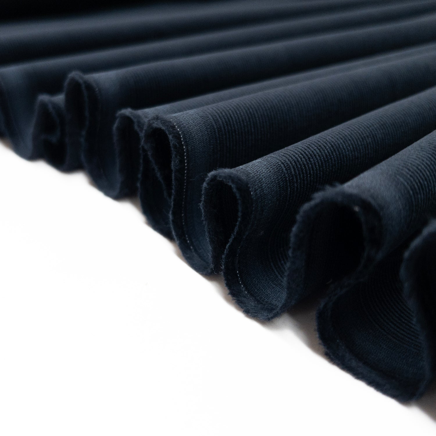 Baby Corduroy shirting fabric in dark blue folded in a ribbon to illustrate lightweight drape of fabric