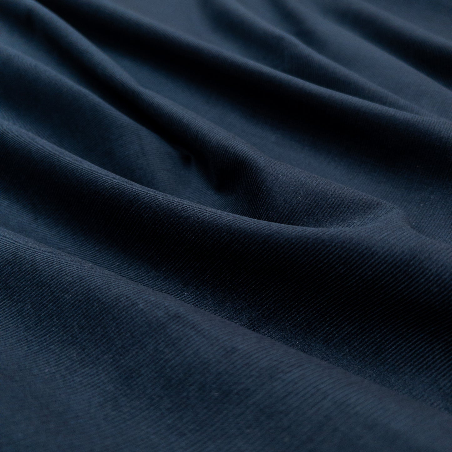 Face view with gentle folds of this dark blue 100% organic cotton baby corduroy shirting fabric.