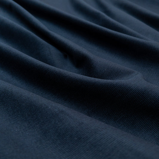 Face view with gentle folds of this dark blue 100% organic cotton baby corduroy shirting fabric.