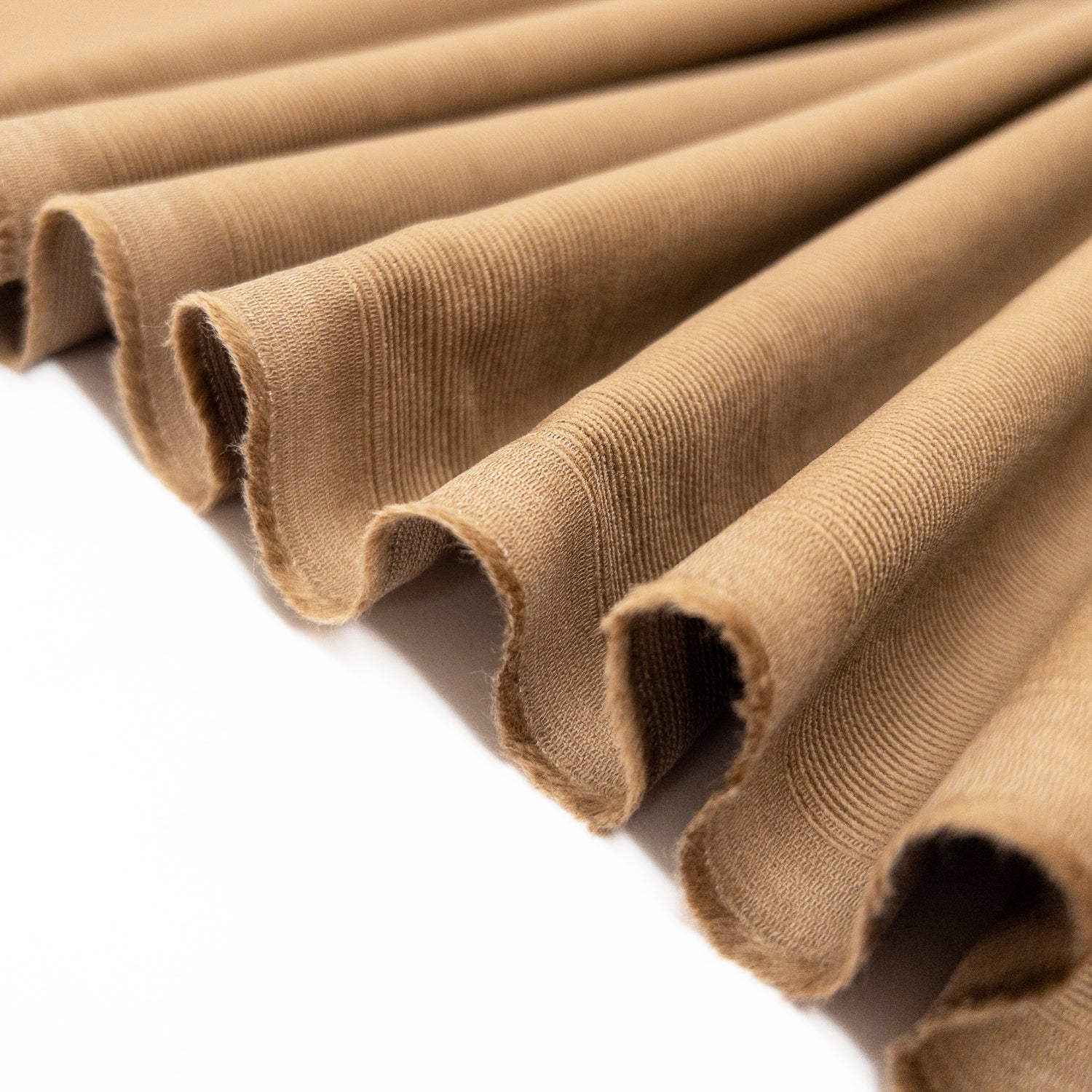 Shirting garment fabric of baby corduroy in a light brown is folded in a ribbon to demonstrate lightweight character