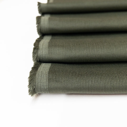 up close view of 100% organic cotton apparel fabric in an earthy green to illustrate the fine ribs of this baby corduroy