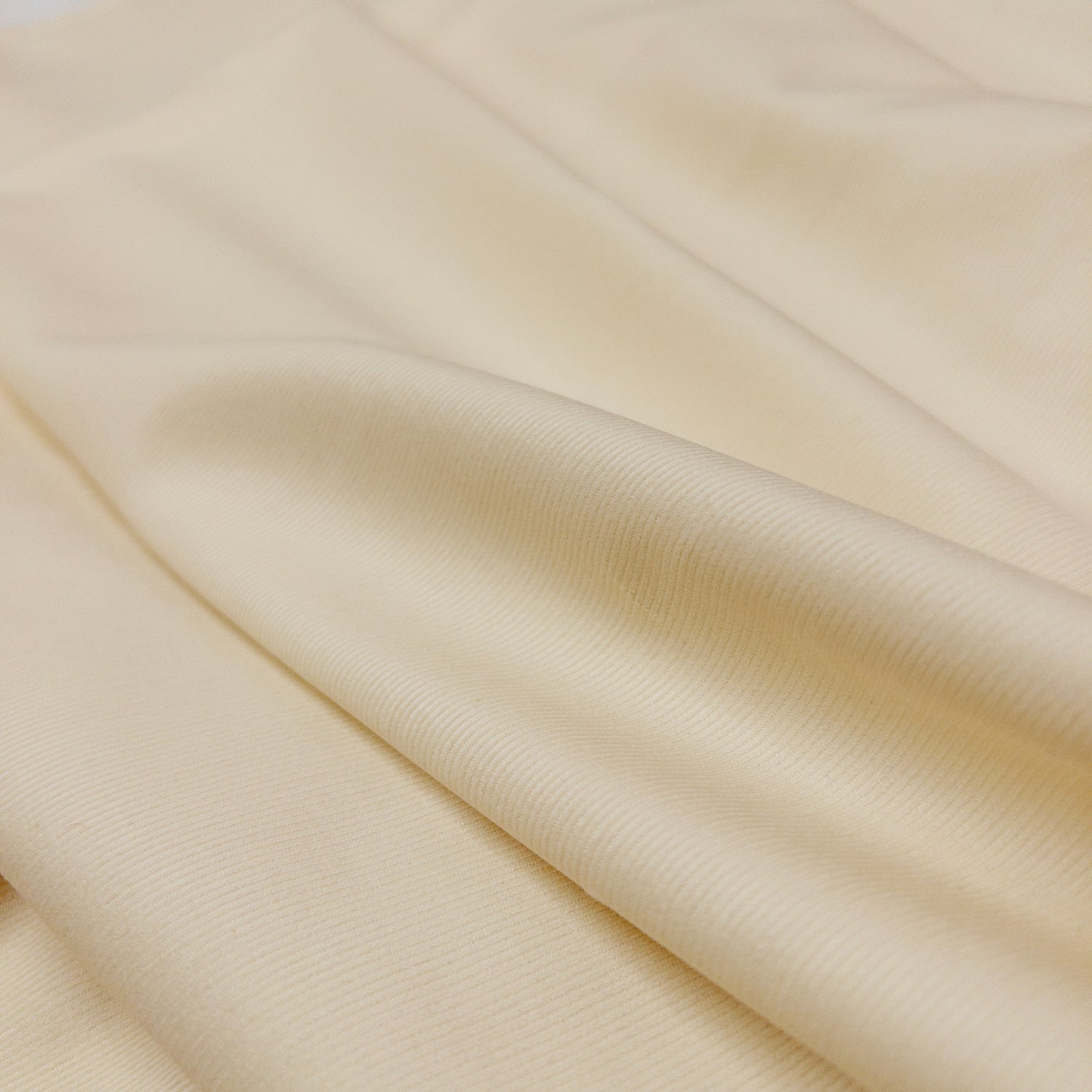 view of the face of fabric with slight folds in this 100% organic cotton baby corduroy apparel fabric is soft white